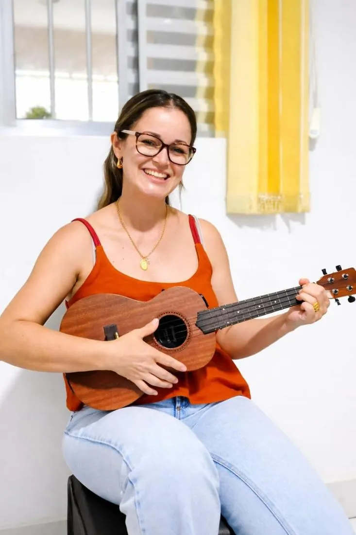 Aluna adulta sorrindo com seu ukulele na Spasso Musical